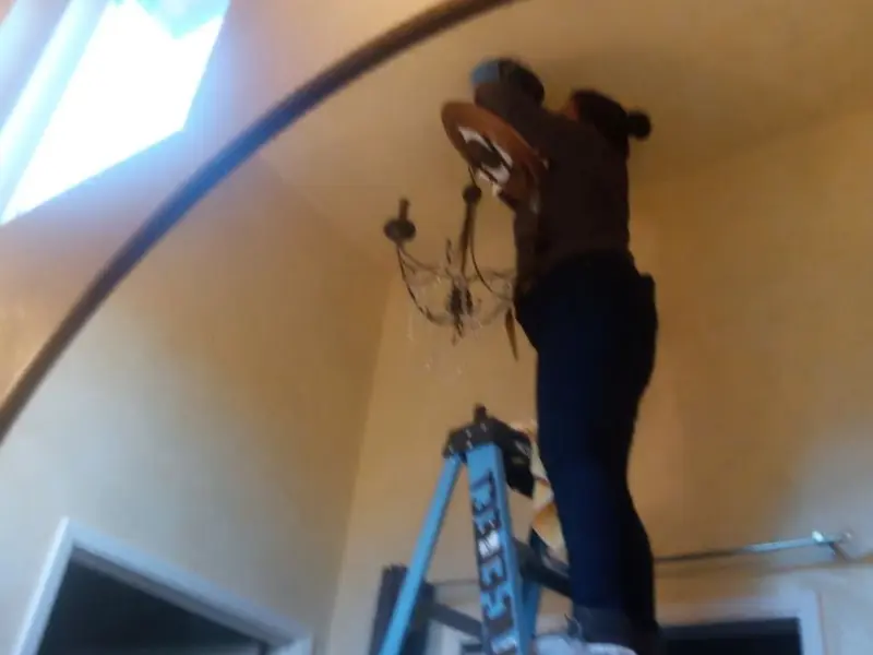 Electrician installing a chandelier in a Eagle Point residence